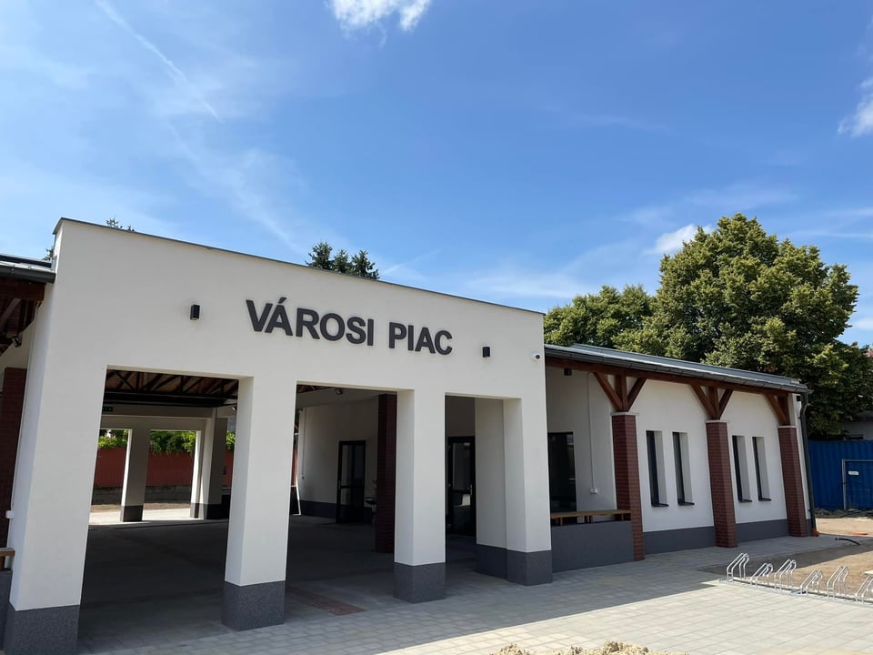 A téglási Városi piac fehér homlokzata, oszlopsora és fedett bejárata.